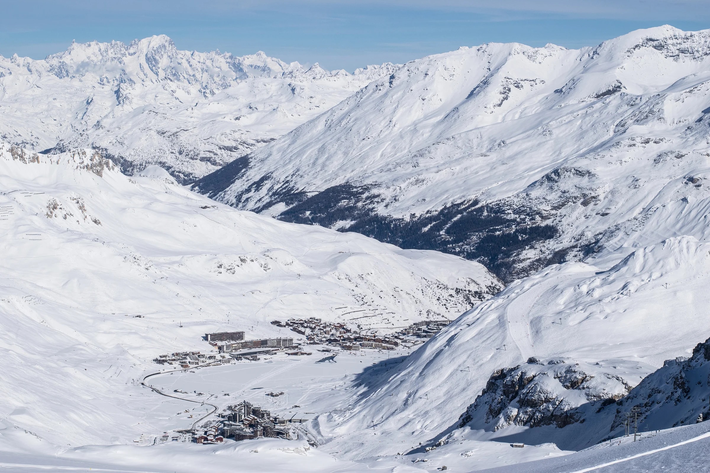 Tignes le Lac and Val Claret in a snow-covered valley, seen from the ski area, with the Mont Blanc massif on the horizon.