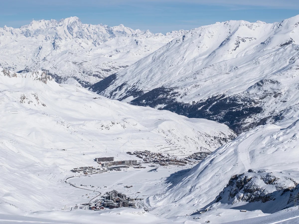 Tignes le Lac und Val Claret in einem verschneiten Tal, vom Skigebiet aus gesehen, am Horizont das Mont-Blanc-Massiv.